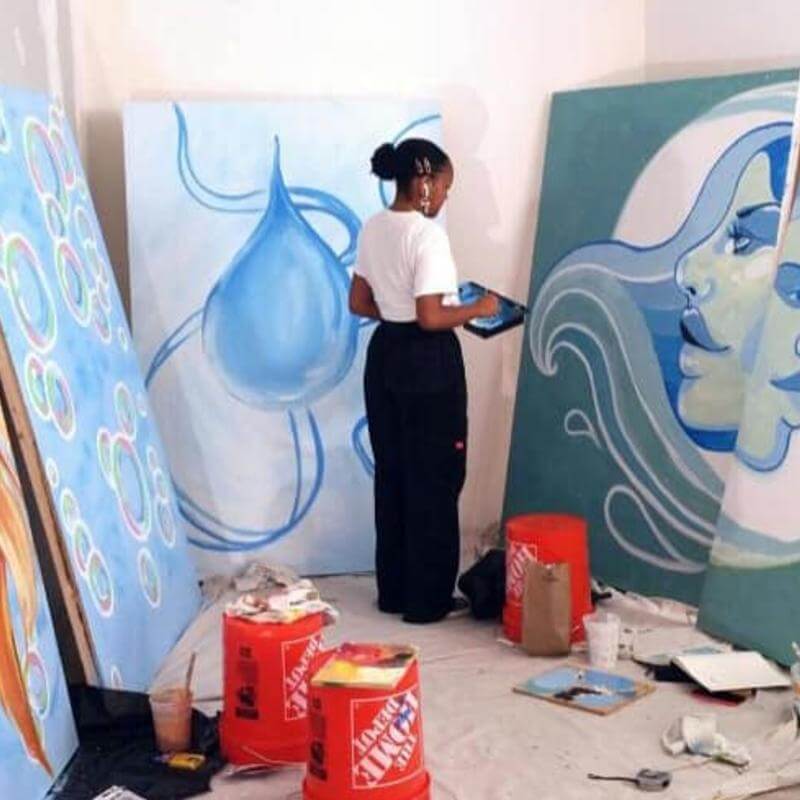 A Howard art student surrounded by painted canvases.