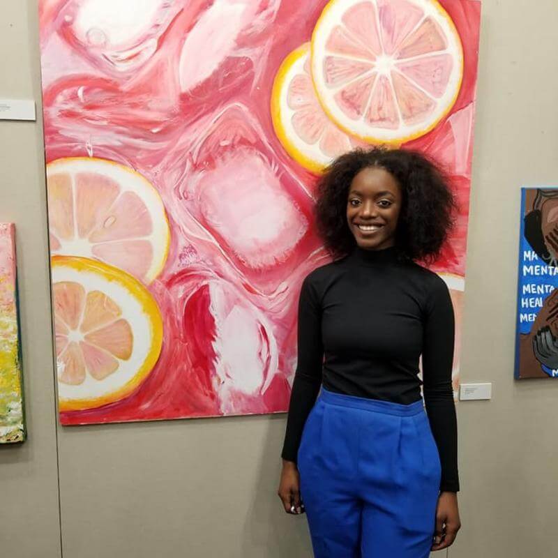 A student standing next to her painting.