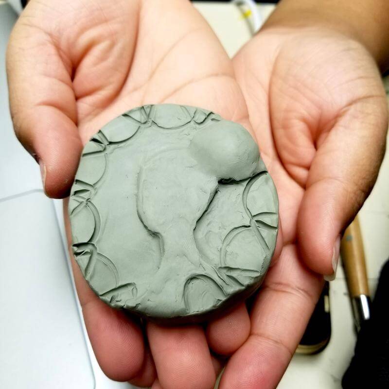 A sculpted piece of clay in a student's hands.