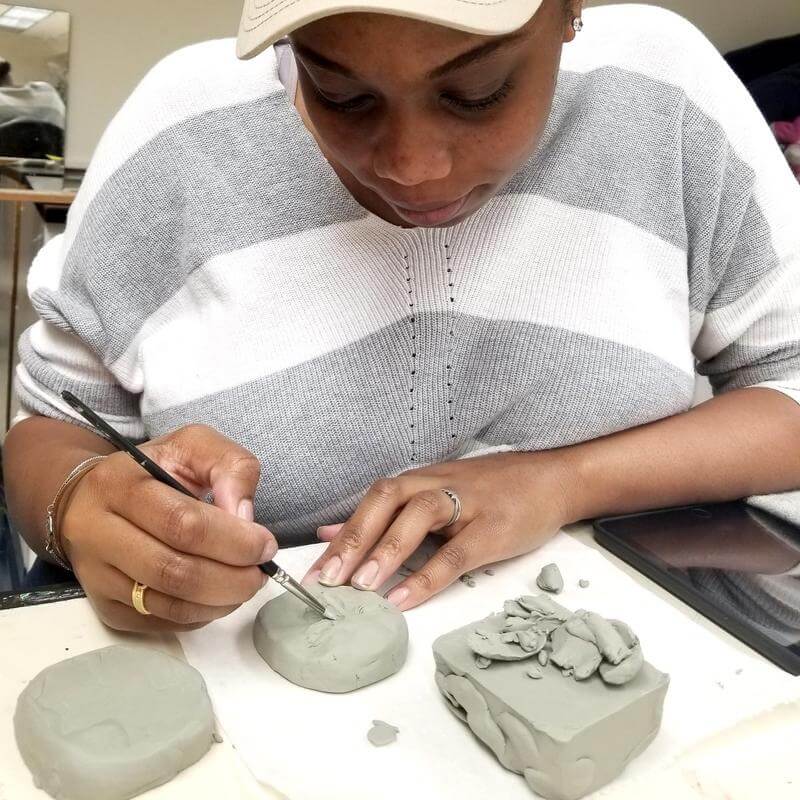 A student working on a clay sculpture.
