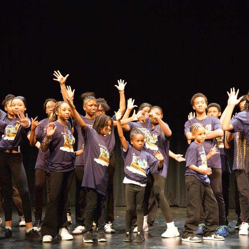 students with their arms raised performing on stage