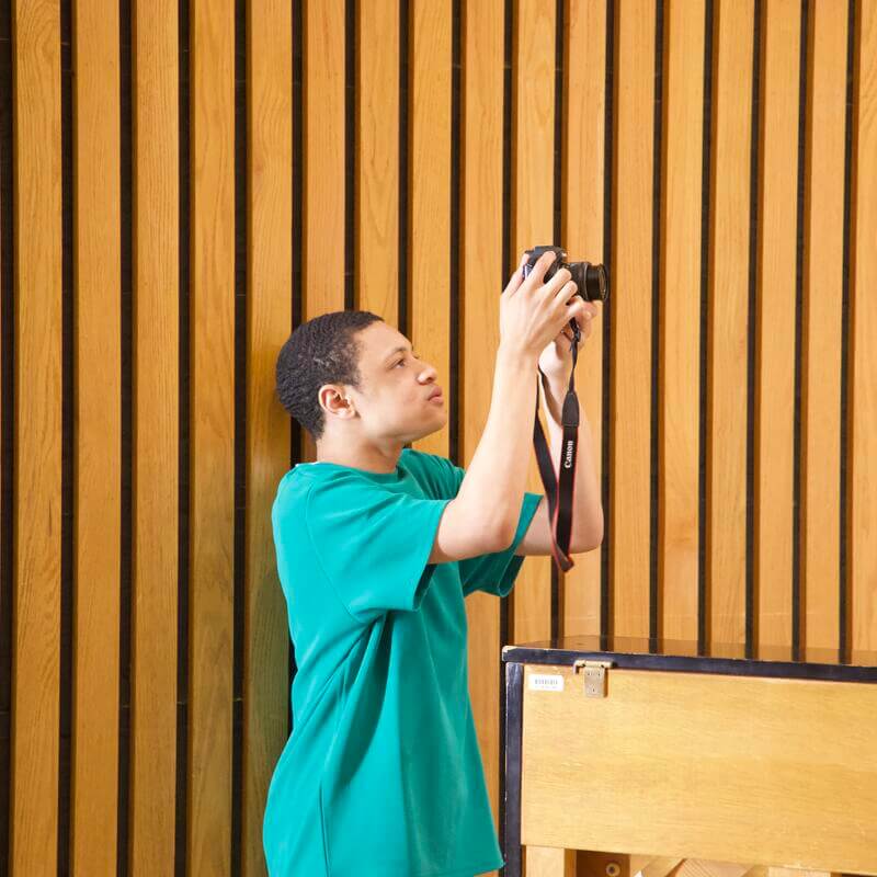 young man in green shirt holding a camera taking a picture