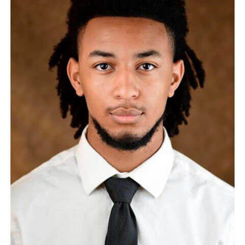Nathaniel Malachi MItchell, African American male with black hair pulled back, long sleeved white shirt and black tie