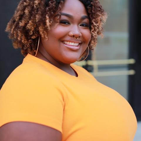 Victoria Hunter, African American female with curly gold and black hair, gold nose piercings, gold hop earrings, wearing a yellow short sleeved shirt