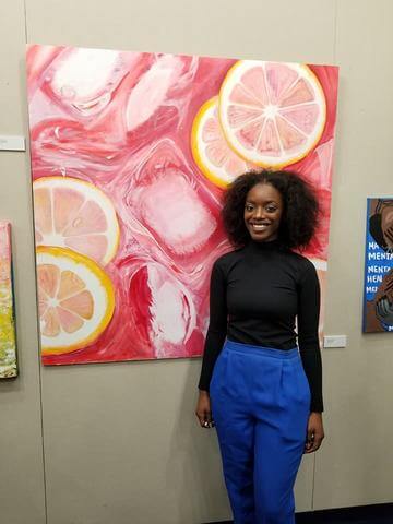 A student standing next to her painting.