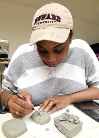 A student working on a clay sculpture.