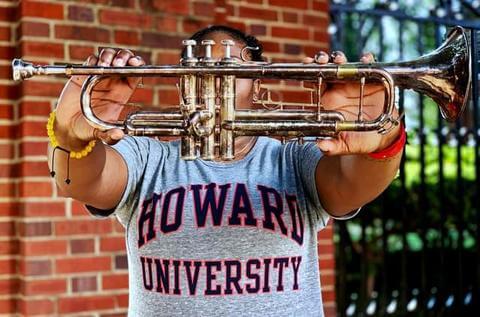 A Howard University musician holding out a trumpet.