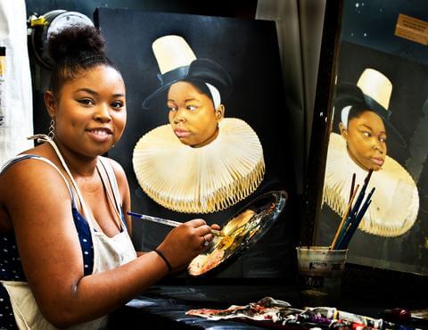 An art student presenting a painted portrait.