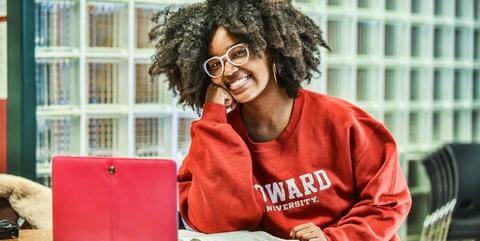 African American female in red Howard U shirt with computer