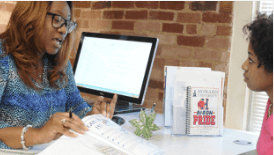 Female student sitting in front of desk speaking with female administrator