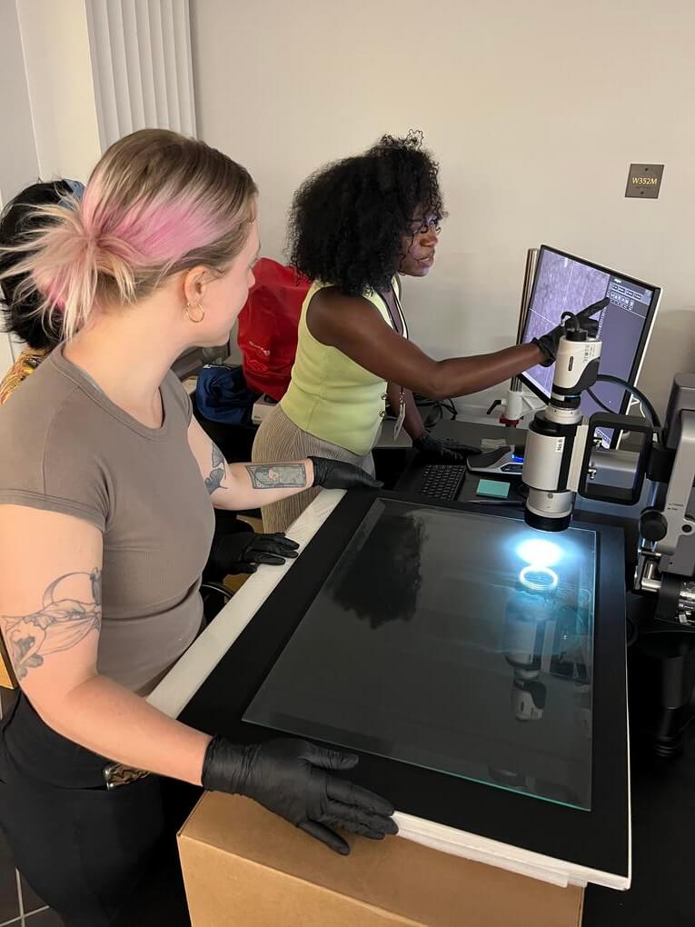 Mykayla Osborne (right) uses a digital microscope as [full name and title] looks on during the Six-Week Introduction to Practical Conservation.